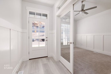 Doorway with a decorative wall, a wainscoted wall, french doors, ceiling fan, and carpet floors