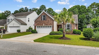 Traditional-style house featuring brick siding, driveway, a front yard, and a garage