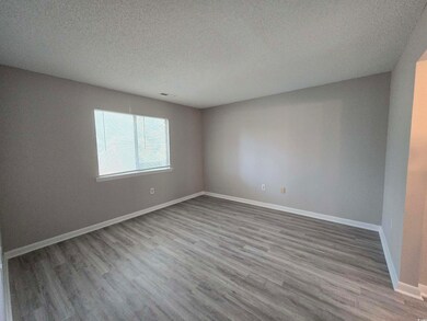 Empty room with a textured ceiling and light wood-