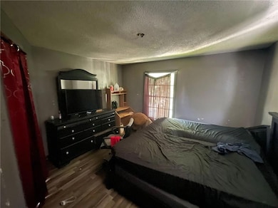 Bedroom with a textured ceiling and wood finished floors