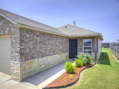 View of exterior entry with a shingled roof, brick siding, and an attached garage
