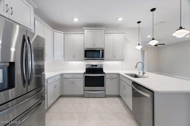 Kitchen with sink, hanging light fixtures, ceiling fan, kitchen peninsula, and stainless steel appliances