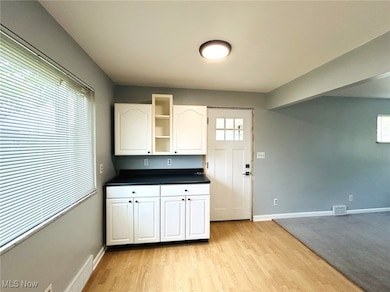 Kitchen with dark countertops, white cabinetry, open shelves, and light wood-style flooring