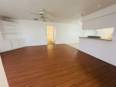 Unfurnished living room with dark wood-style flooring, a textured ceiling, and ceiling fan