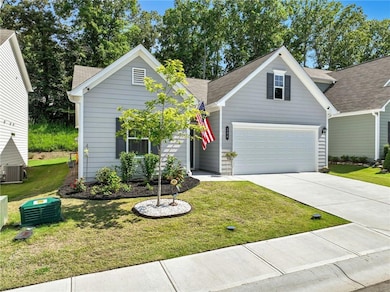 Traditional-style home featuring concrete driveway, a front yard, a garage, and roof with shingles