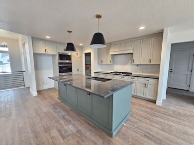 Kitchen featuring gray cabinets, decorative backsplash, appliances with stainless steel finishes, a large island, and pendant lighting