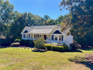 View of front of house with covered porch, a front lawn, and roof with shingles