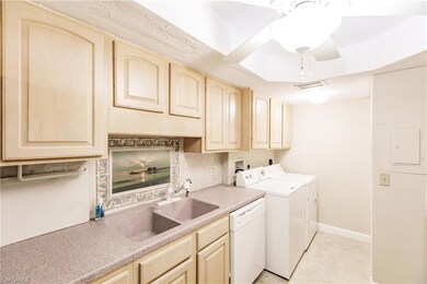 Clothes washing area featuring separate washer and dryer, sink, and light tile patterned floors