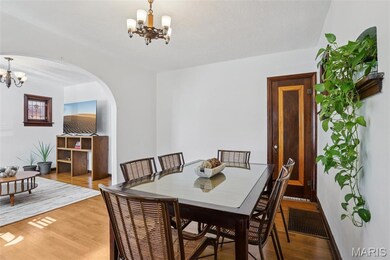 Dining space with a chandelier, wood finished floors, and arched walkways