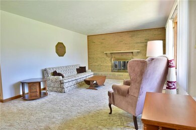Carpeted living room with brick wall and a firepla