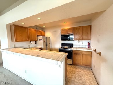 Kitchen featuring white appliances, tile counters,