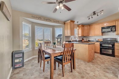 Dining room featuring vaulted ceiling, stone finish floors, and ceiling fan