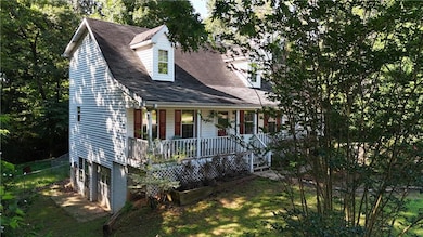 Cape cod house with covered porch, a garage, and driveway
