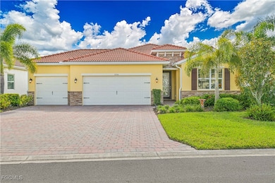Mediterranean / spanish-style house with stone siding, a front yard, stucco siding, and decorative driveway