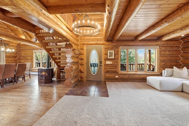 Foyer featuring a chandelier, a wooden ceiling with exposed beams, a wood stove, rustic walls, and wood finished floors