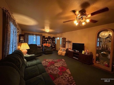 Carpeted living area with ceiling fan and a textured ceiling