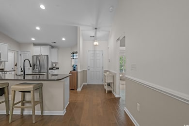 Kitchen with dark countertops, white cabinetry, dark wood-type flooring, stainless steel fridge with ice dispenser, and recessed lighting