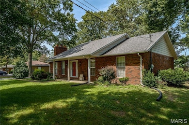 Single story home with brick siding, a front yard, covered porch, and a chimney