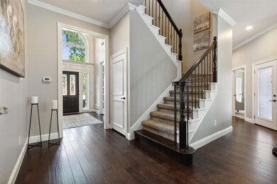 Entrance foyer featuring dark wood-type flooring, a towering ceiling, and crown molding