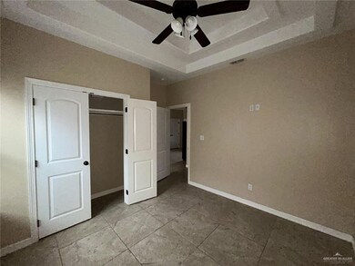 Unfurnished bedroom with a raised ceiling, baseboards, ceiling fan, and a closet