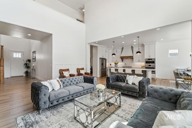Living area with plenty of natural light, recessed lighting, light wood-style flooring, and a towering ceiling