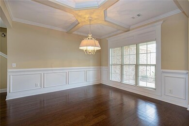 Spare room featuring a wainscoted wall, coffered ceiling, a decorative wall, dark wood-style flooring, and ornamental molding