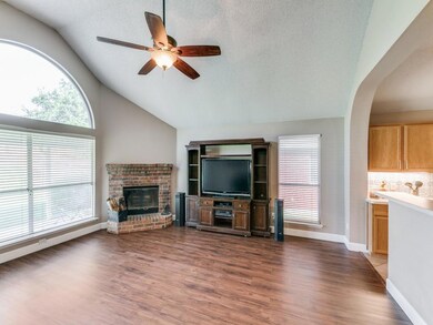 Living room featuring ceiling fan, wood-style flooring, a fireplace, and a healthy amount of sunlight