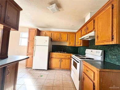Kitchen with white appliances, light tile patterned floors, sink, backsplash, and a textured ceiling