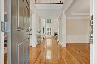 Foyer entrance featuring light wood-style floors, a decorative wall, ornamental molding, a wainscoted wall, and a fireplace