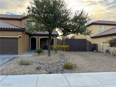 View of front facade featuring a gate, stucco siding, an attached garage, and a tiled roof