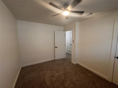 Unfurnished room featuring dark carpet and a ceiling fan