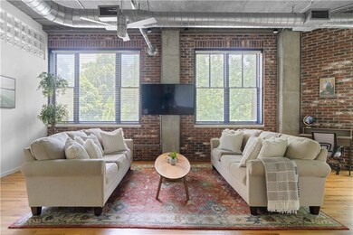 Living area featuring brick wall, wood finished floors, and plenty of natural light