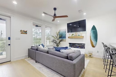 Living room with ceiling fan, light wood finished floors, recessed lighting, and a glass covered fireplace