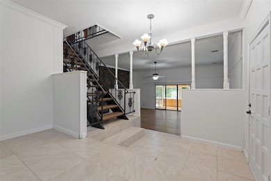 Entryway with a chandelier, ceiling fan, stairway, and ornamental molding