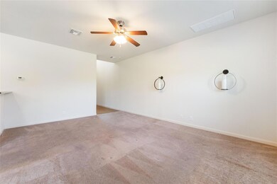 Carpeted spare room featuring a ceiling fan, base