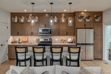 Kitchen featuring appliances with stainless steel finishes, glass insert cabinets, decorative backsplash, a kitchen breakfast bar, and recessed lighting