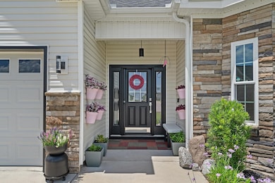 View of exterior entry featuring stone siding and a shingled roof