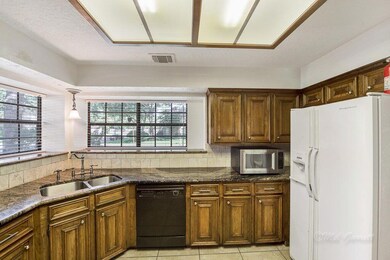 KITCHEN - looks onto the beautiful front yard and opens to the breakfast, dining, and family rooms.