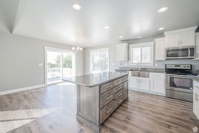 Kitchen with stainless steel appliances, a center island, dark stone countertops, white cabinets, and a textured ceiling