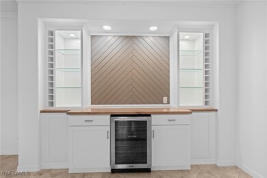 Bar featuring baseboards, beverage cooler, crown m