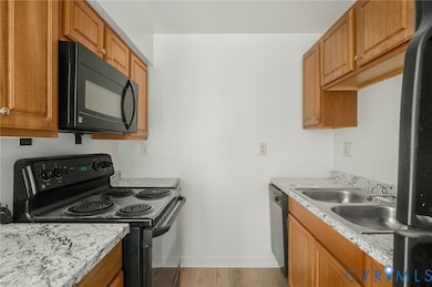 Kitchen with black appliances, light wood-style floors, and brown cabinets
