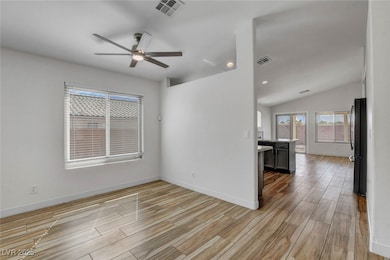 Empty room featuring wood finish floors, a ceiling fan, vaulted ceiling, and recessed lighting