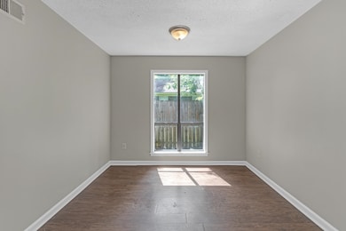 Empty room with dark wood-type flooring and a textured ceiling