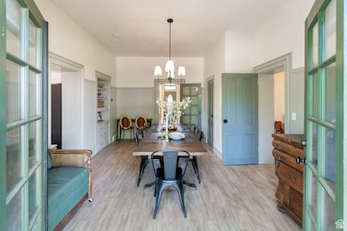 Dining room featuring wood finished floors, a chandelier, and wainscoting