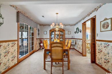 Dining room with light carpet and a chandelier