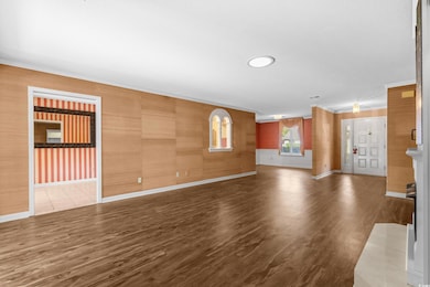 Unfurnished living room featuring wood finished floors and ornamental molding