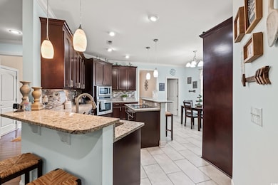 Kitchen featuring stainless steel appliances, ornamental molding, a kitchen bar, a peninsula, and decorative backsplash