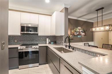 Kitchen featuring stainless steel appliances, a sink, light countertops, crown molding, and tasteful backsplash