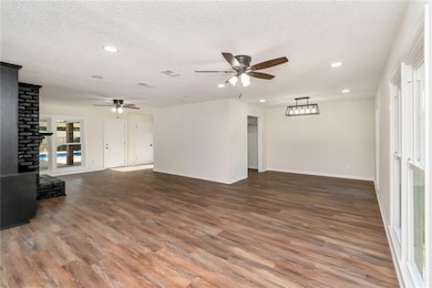 Unfurnished living room featuring a ceiling fan, wood finished floors, recessed lighting, baseboards, and a textured ceiling