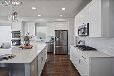 Kitchen with appliances with stainless steel finishes, a sink, recessed lighting, light countertops, and white cabinets